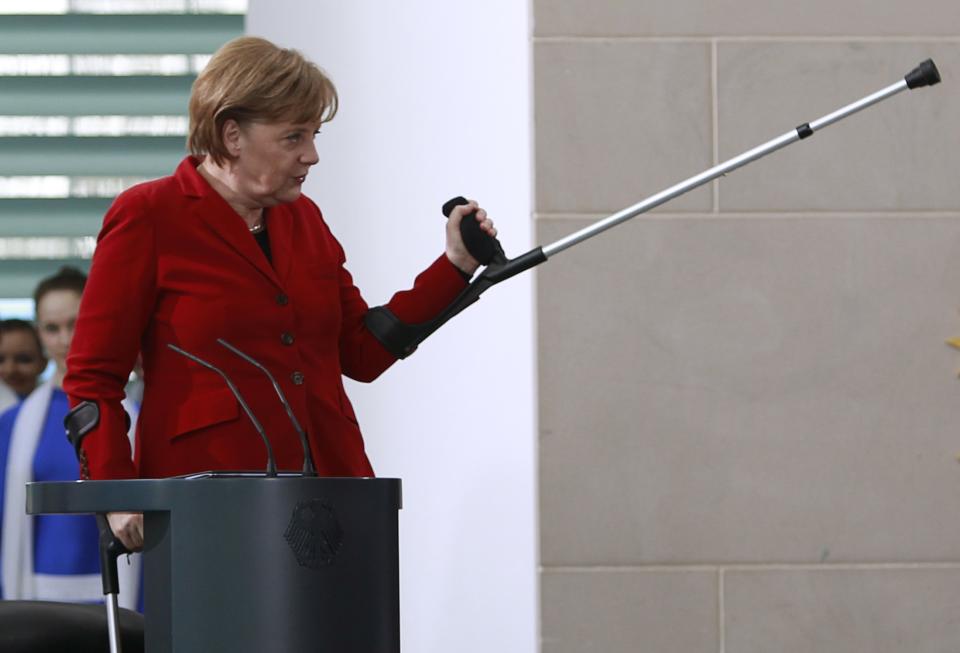 File photo of German Chancellor Angela Merkel gesturing with her crutch during a reception of people working in honorary offices during a reception at the Chancellery in Berlin, April 5, 2011. German Chancellor Angela Merkel has fractured her pelvis in a cross-country skiing accident and is walking with the help of crutches, forcing her to call off some foreign visits and official appointments, her spokesman said January 6, 2014. Merkel fell while skiing over the Christmas vacation. What she first thought was heavy bruising turned out to be a partial fracture, meaning she must take it easy for three weeks and work from home where possible, said her spokesman Steffen Seibert. REUTERS/Thomas Peter/Files (GERMANY - Tags: POLITICS SOCIETY)