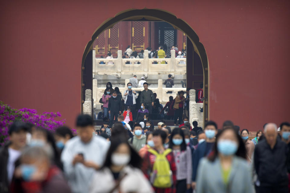 Visitors wearing face masks to protect against the coronavirus walk through in a doorway at the Temple of Heaven in Beijing, Thursday, Oct. 1, 2020. Millions of Chinese tourists usually would use their week-long National Day holidays to travel abroad. This year, travel restrictions due to the coronavirus pandemic mean that some 600 million tourists - about 40% of the population - will travel within China during the holiday that began Thursday, according to Ctrip, China's largest online travel agency. (AP Photo/Mark Schiefelbein)