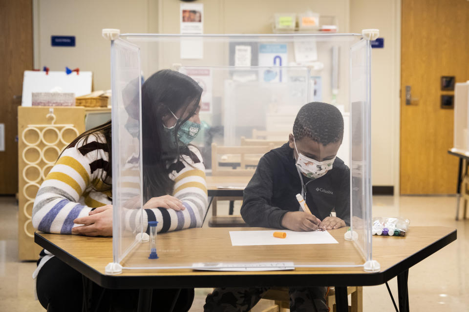 FILE - In this Jan. 11, 2021 file photo, pre-kindergarten teacher Sarah McCarthy works with a student at Dawes Elementary in Chicago. Chicago Public Schools should allow students back into classrooms in no more than 100 facilities and then gradually reopen others, an organization of school principals proposed Wednesday, Jan. 27, 2021, saying most of them doubt the nation's third-largest school district can safely handle a mass reopening. (Ashlee Rezin Garcia/Chicago Sun-Times via AP, Pool File)