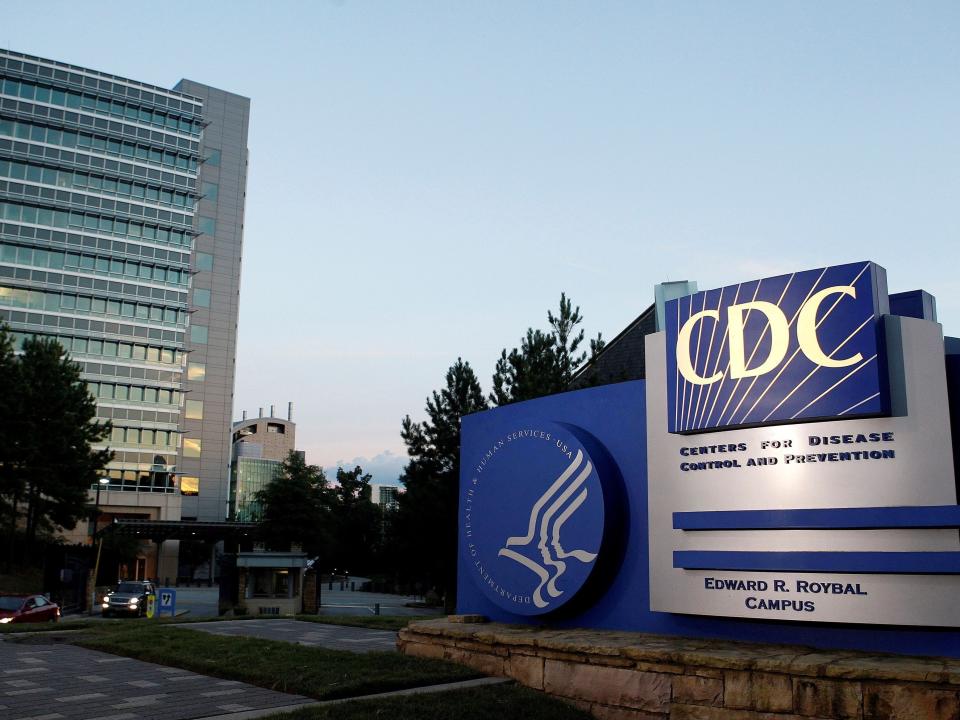 The blue-and-white CDC sign in front of the agency's Atlanta headquarters at sunset