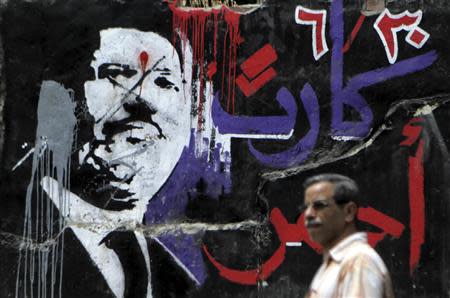 A man walks past graffiti depicting ousted Egyptian President Mohamed Mursi in downtown Cairo September 2, 2013. REUTERS/Amr Abdallah Dalsh