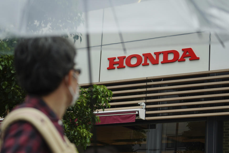 A man wearing a protective mask to help curb the spread of the coronavirus walks past the logo of Honda Motor Company Thursday, May 13, 2021, in Tokyo. Honda swung into the black in January-March, recording a 213 billion yen ($2 billion) profit, despite the ongoing uncertainties unleashed by the coronavirus pandemic, the results, released Friday, May 14, 2021. (AP Photo/Eugene Hoshiko)