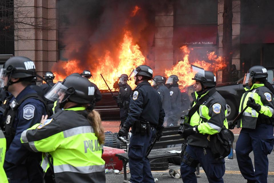 Police officers move protestors away from a car that was set on fire during protests near the inauguration of President Donald Trump in Washington, DC, U.S., January 20, 2017.