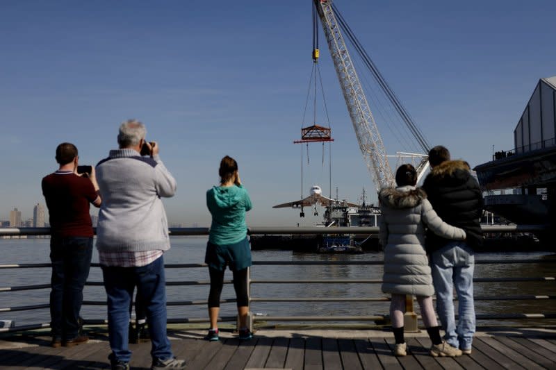 People watch from a pier as the British Airways Concorde is lifted by crane on to Pier 83 at the Intrepid Museum in New York City. The supersonic jet, which holds the record for the fastest transatlantic crossing by a passenger aircraft, made its return to the Intrepid Museum following a months-long restoration project at GMD Shipyard in Brooklyn Navy Yard. Photo by John Angelillo/UPI
