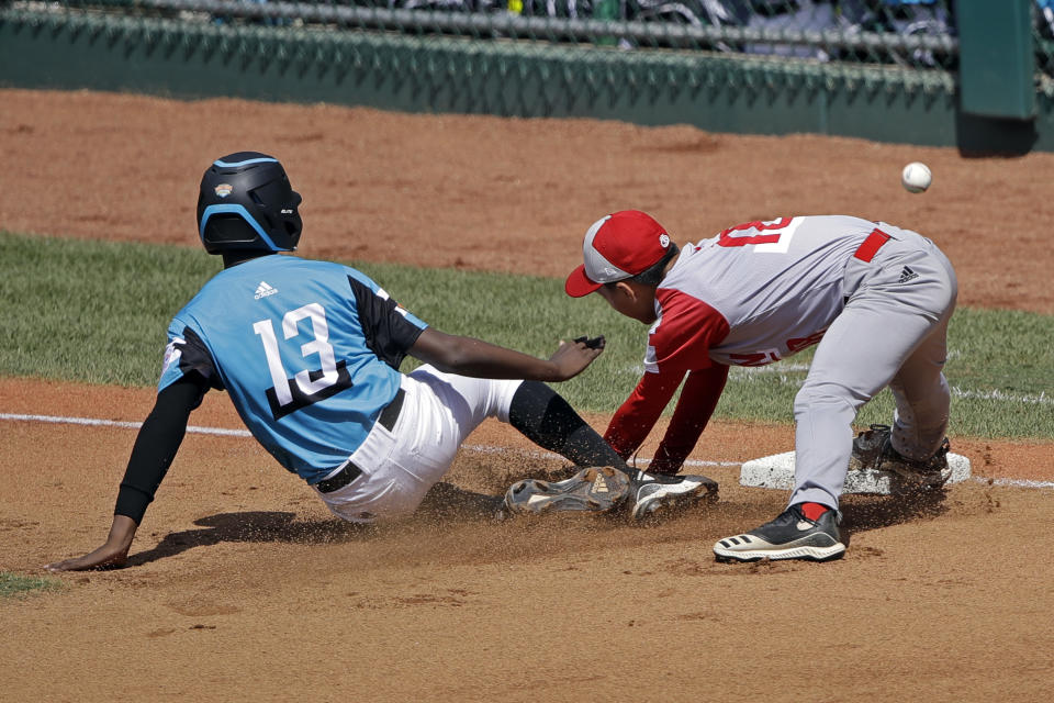 Curacao's Jurdrick Profar (13) slides into third base as the ball gets away from Japan's Yuto Misaki (18) and scored on the play in the first inning of the International Championship baseball game at the Little League World Series tournament in South Williamsport, Pa., Saturday, Aug. 24, 2019. (AP Photo/Tom E. Puskar)