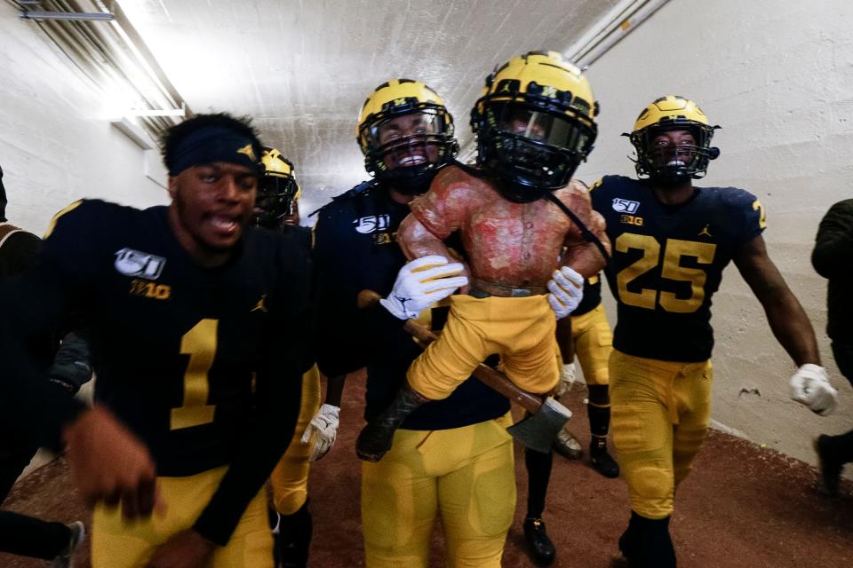 Michigan linebacker Devin Gil holds up the Paul Bunyan Trophy next to defensive back Ambry Thomas, left, and running back Hassan Haskins as they walk up the tunnel after U-M's 44-10 win over MSU at Michigan Stadium on Saturday, Nov. 16, 2019.