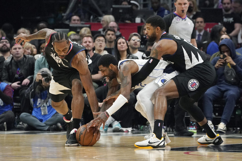 Dallas Mavericks guard Kyrie Irving, center, scrambles for a ball along with Los Angeles Clippers forward Kawhi Leonard, left, and forward Paul George during the second half of an NBA basketball game Wednesday, Feb. 8, 2023, in Los Angeles. (AP Photo/Mark J. Terrill)