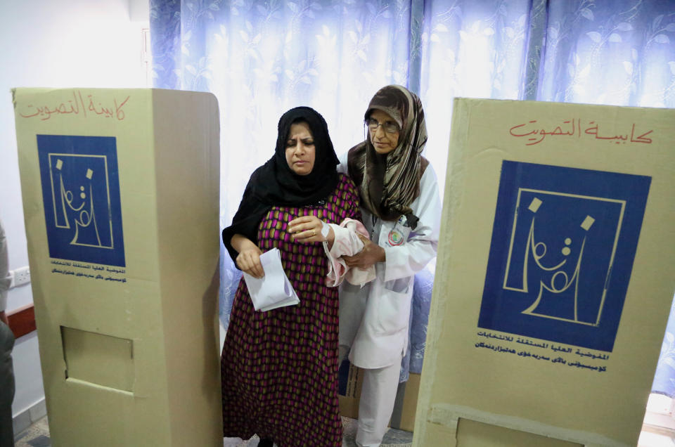 An Iraqi patient, left, prepares to cast her vote at a polling center in Baghdad, Iraq, Monday, April 28, 2014. Amid tight security, some one million Iraqi army and police personnel have started voting for the nation's new parliament. (AP Photo/Karim Kadim)