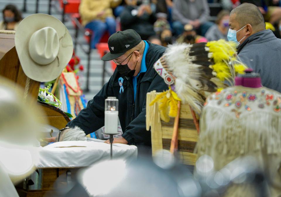 Carl Old Person places silver dollars in the casket of his uncle, Chief Earl Old Person. before Friday's funeral service at Browning High School in Browning, Mont.