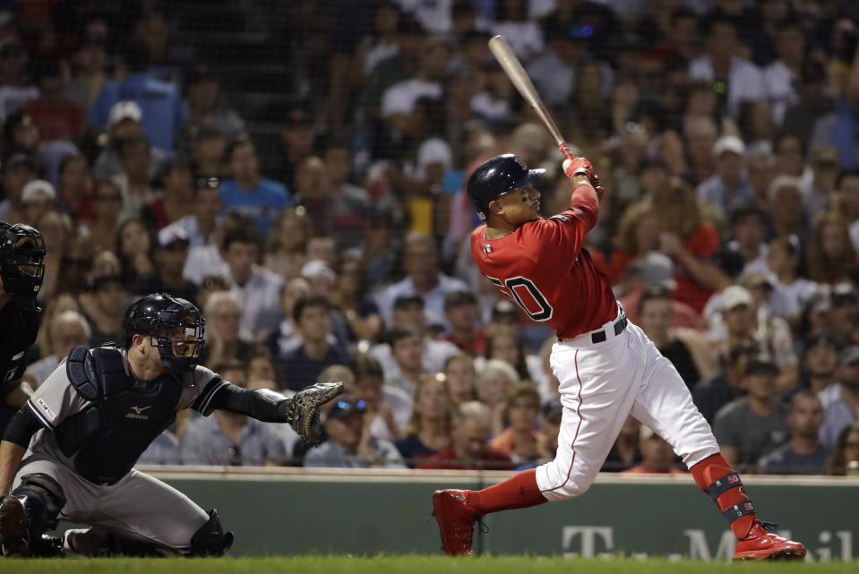 Boston Red Sox's Mookie Betts hits a two-run homer in front of New York Yankees catcher Austin Romine in the fourth inning of a baseball game at Fenway Park, Friday, July 26, 2019, in Boston. It was his third home run of the game. (AP Photo/Elise Amendola)