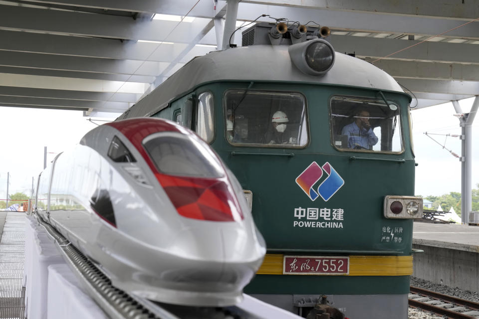 A train engine rolls past a model of a high-speed train displayed at the construction site of a Jakarta-Bandung Fast Railway station in Tegalluar, West Java, Indonesia, Thursday, Oct. 13, 2022. The 142-kilometer (88-mile) high-speed railway worth $5.5 billion is being constructed by PT Kereta Cepat Indonesia-China, a joint venture between an Indonesian consortium of four state-owned companies and China Railway International Co. Ltd. The joint venture says the trains that will be the fastest in Southeast Asia. (AP Photo/Dita Alangkara)