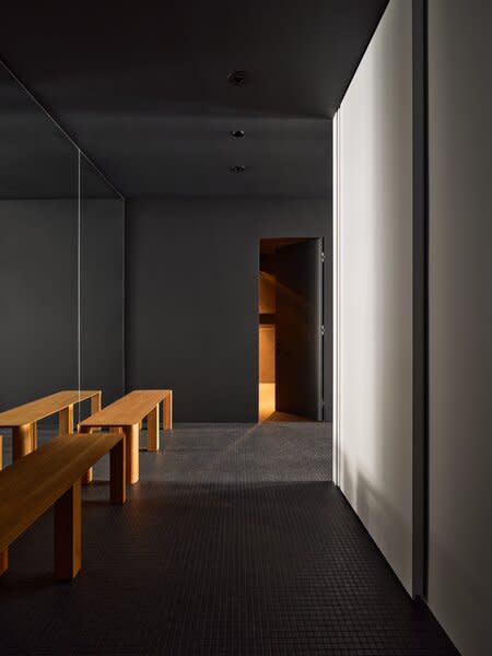 Looking in the opposite direction reveals how designer Louis Béliveau of La Firme embraced the lack of light in this part of the apartment, instead emphasizing it with ample dark finishes, like the 1x1-inch Daltile on the floor. A mirrored wall does catch some sun from the living room windows. 