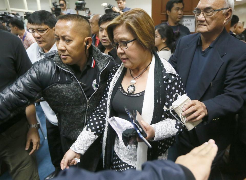 Opposition Senator Leila de Lima is escorted by Senate security to address the media after a warrant for her arrest was issued by a regional trial court Thursday, Feb. 23, 2017, in suburban Pasay city, south of Manila, Philippines. The Philippine court has issued an arrest warrant on drug charges for the senator and former top human rights official who is one of the most vocal critics of President Rodrigo Duterte and his deadly crackdown on illegal drugs. De Lima has vehemently denied the charges, which she says are part of Duterte's attempt to intimidate critics of his crackdown, which has left more than 7,000 drug suspects dead. (AP Photo/Bullit Marquez)