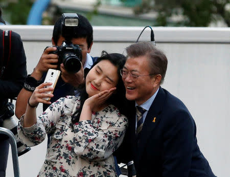 Moon Jae-in, presidential candidate of the Democratic Party of Korea, takes a selfie with a supporter during his election campaign rally in Seoul, South Korea, May 6, 2017. REUTERS/Kim Kyung-Hoon