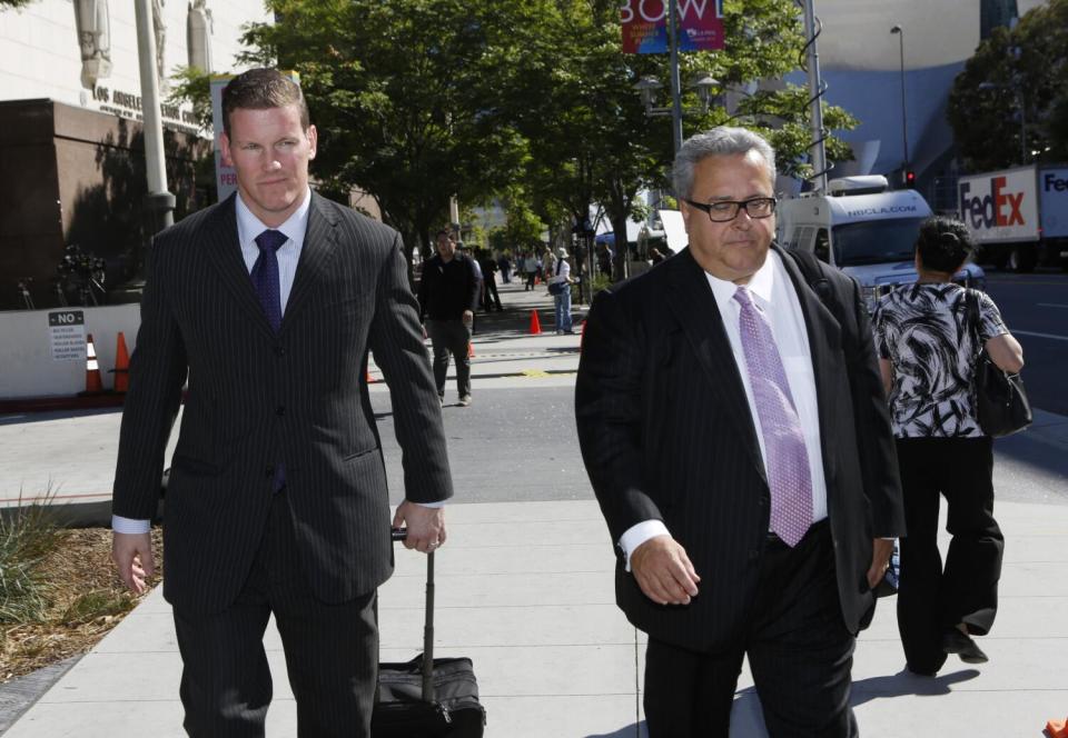 Two men walk while wearing dark suits.