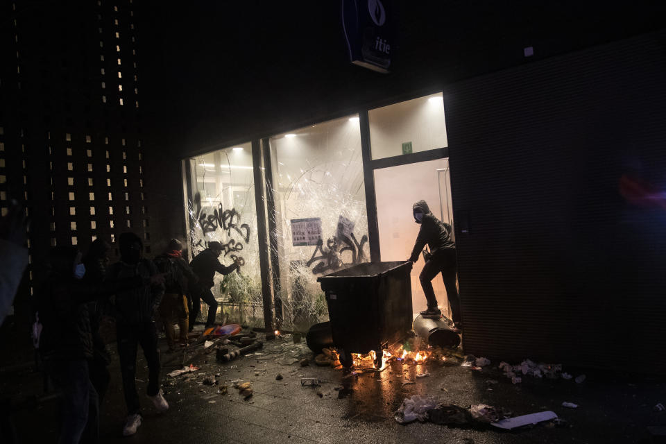 Protestors outside a police office in the Belgium capital, Brussels, Wednesday, Jan. 13, 2021, at the end of a protest asking for authorities to shed light on the circumstances surrounding the death of a 23-year-old Black man who was detained by police last week in Brussels. The demonstration in downtown Brussels was largely peaceful but was marred by incidents sparked by rioters who threw projectiles at police forces and set fires before it was dispersed. (AP Photo/Francisco Seco)