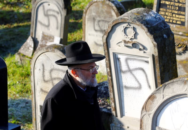 FILE PHOTO: A man walks past graves desecrated with swastikas at the Jewish cemetery in Westhoffen