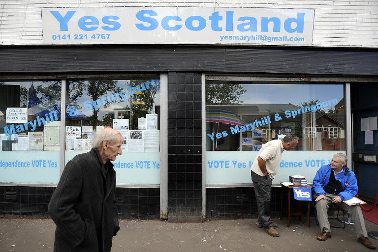 A pedestrian walks past the 'Yes Scotland' campaign office in Maryhill, Glasgow, on August 19, 2014