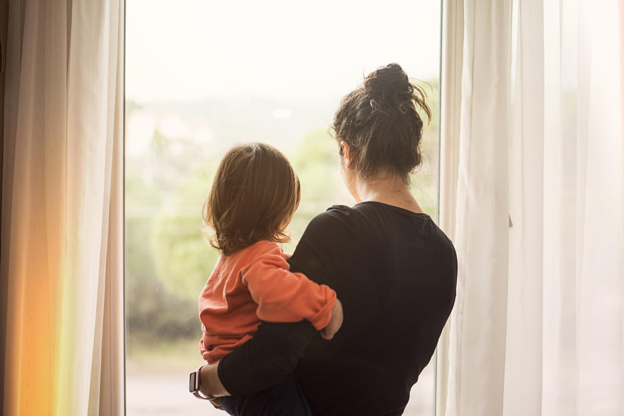 Mother and son looking out of window from home