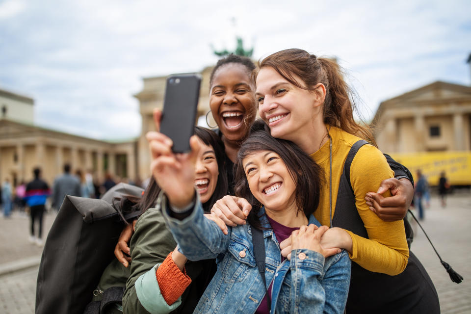 Cheerful multi-ethnic female friends taking selfie against Brandenburg Gate during vacation