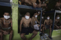 Imprisoned gang members, wearing protective face masks, sit inside a group cell during a media tour of the prison in Quezaltepeque, El Salvador, Friday, Sept. 4, 2020. President Nayib Bukele denied a report Friday that his government has been negotiating with one of the country’s most powerful gangs to lower the murder rate and win their support in mid-term elections in exchange for prison privileges. (AP Photo/Salvador Melendez)