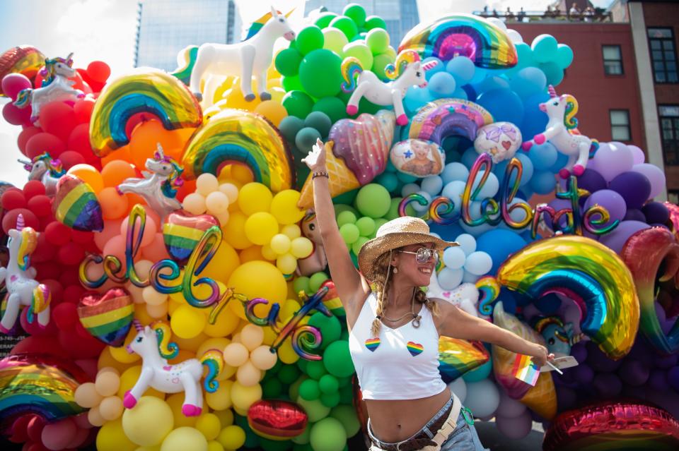 A parade watcher stands to pose in front of a truck full of balloons on Broadway watching the Pride Festival Parade in Nashville, Tenn., Saturday, June 25, 2022.