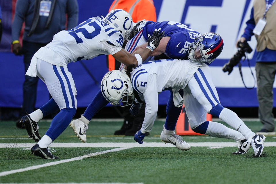 New York Giants' Daniel Bellinger (82) is tackled by Indianapolis Colts' Stephon Gilmore (5) and Julian Blackmon (32) during the first half of an NFL football game, Sunday, Jan. 1, 2023, in East Rutherford, N.J. (AP Photo/Bryan Woolston)