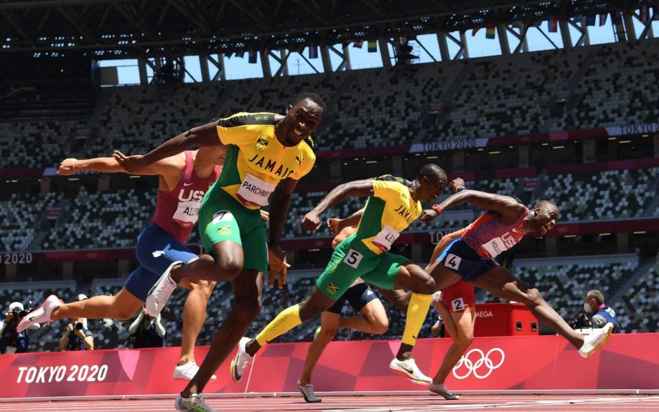 Jamaica's Hansle Parchment (L) crosses the finish line to win ahead of second-placed USA's Grant Holloway (R) and third-placed Ronald Levy  - AFP