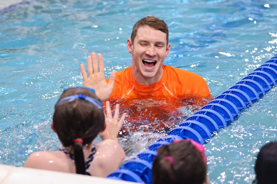 Ryan Murphy, a four-time gold medalist swimmer, high-fives a student during a visit to the Goldfish Swim School in Milford, Dec. 2, 2023.