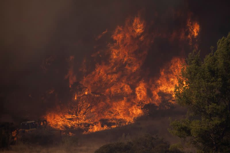 A firefighting bulldozer battles the Bond Fire wildfire near Lake Irvine in Orange County, California