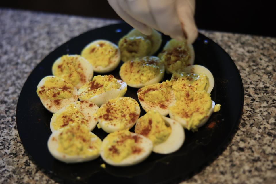 Volunteer Johnny Barnes sprinkles Spanish paprika deviled eggs at Margaret Woods' home in Hastings. Barnes cooked lunch for Woods as part of Pie in the Sky Community Alliance's campaign to provide pricey eggs for needy seniors.