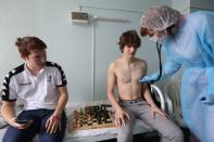 A nurse wearing protective gear checks the health of chess players from France at a hospital in Murmansk