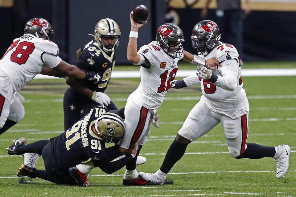 FILE - In this Sunday, Sept. 13, 2020 file photo, Tampa Bay Buccaneers quarterback Tom Brady (12) tries to throw as he is brought down by New Orleans Saints defensive end Trey Hendrickson (91) in the first half of an NFL football game in New Orleans. For all the extraordinary talent the Saints and Buccaneers have at quarterback, running back and receiver, defensive end Cameron Jordan figures that what happens in the trenches will be the decisive factor in their divisional-round playoff clash.(AP Photo/Butch Dill, File)