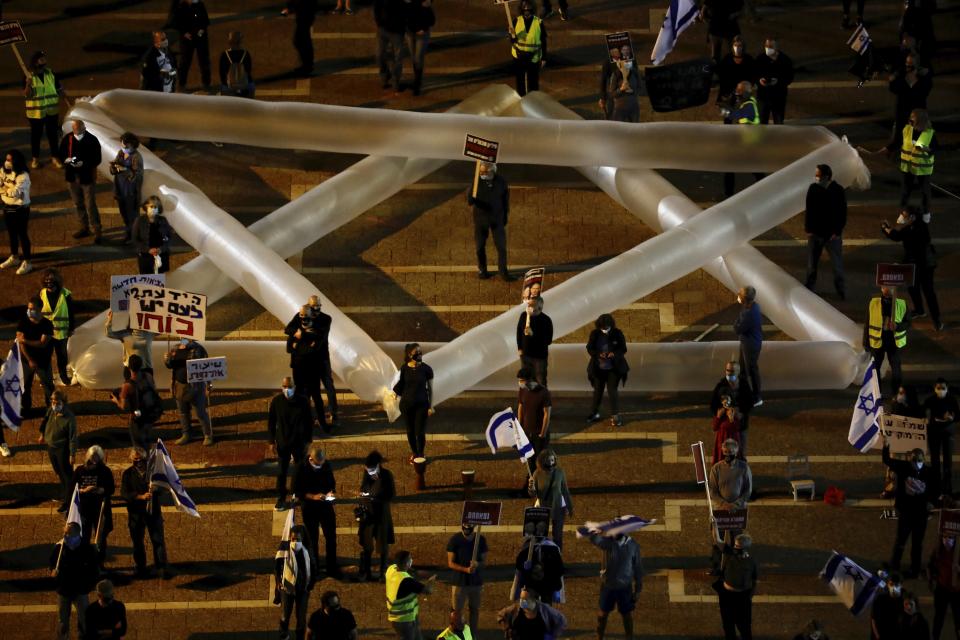 People keep social distance amid concerns over the country's coronavirus outbreak, during a protest against Prime Minister Benjamin Netanyahu and Benny Gantz and government corruption, at Rabin square in Tel Aviv, Israel, Saturday, May 2, 2020. Several thousand Israelis took to the streets on Saturday night, demonstrating against Prime Minister Benjamin Netanyahu's new coalition deal with his chief rival a day before the country's Supreme Court is to begin debating a series of legal challenges to the agreement.(AP Photo/Ariel Schalit)