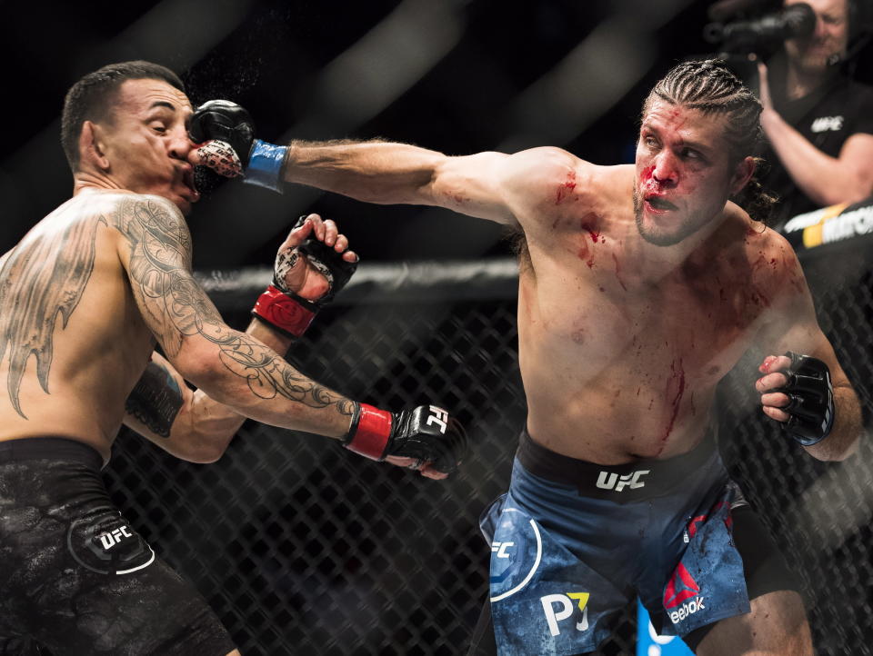 Max Holloway, lefts, take a punch to the face from Brian Ortega during the featherweight championship mixed martial arts bout at UFC 231 in Toronto on Saturday, Dec. 8, 2018. (Nathan Denette/The Canadian Press via AP)