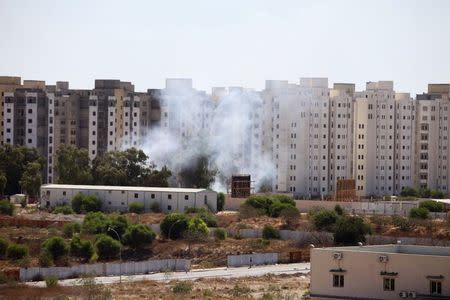 Smoke rises near buildings after heavy fighting between rival militias broke out near the airport in Tripoli July 23, 2014. REUTERS/Hani Amara