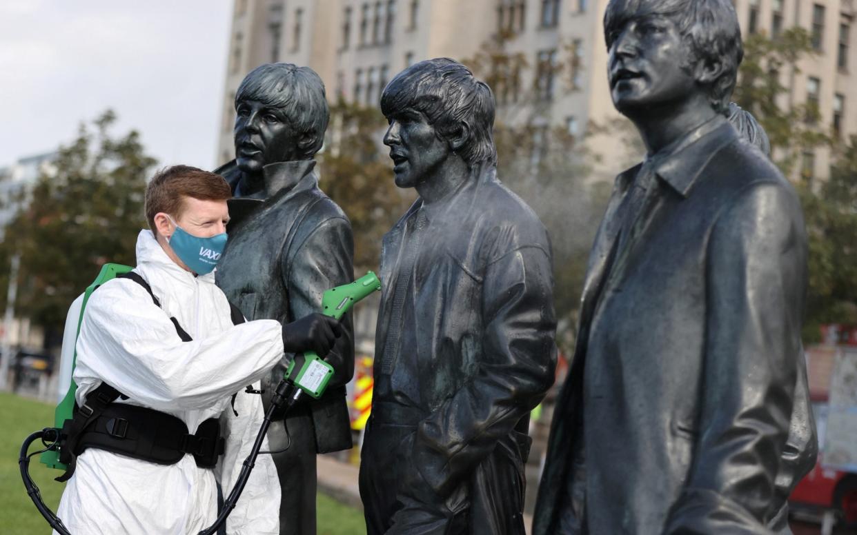 A man disinfects a statue of the Beatles as Liverpool is given tighter rules - Carl Recine/Reuters