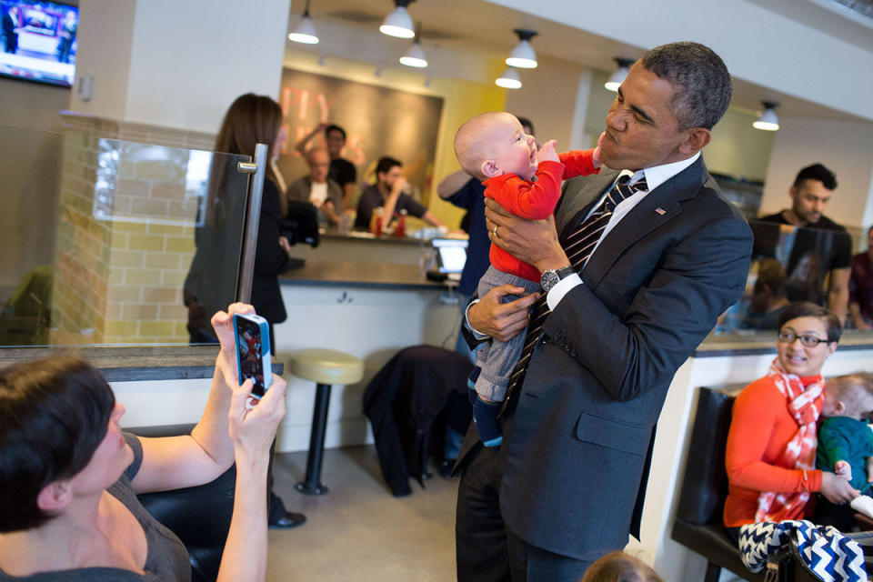Obama holds a baby while greeting patrons at The Coupe restaurant in Washington, D.C., Jan. 10, 2014.