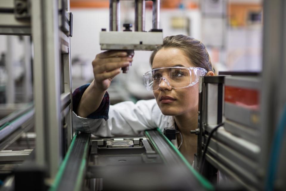 A worker inspecting a device on a factory line.