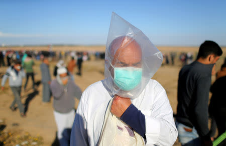 A Palestinian covers his face with a plastic bag to protect himself from tear gas fired by Israeli troops during a protest at the Israel-Gaza border fence, in the southern Gaza Strip May 3, 2019. REUTERS/Ibraheem Abu Mustafa