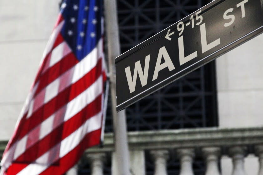 FILE - This Monday, July 15, 2013, file photo shows the American flag and Wall Street sign outside the New York Stock Exchange. Major global stock markets and U.S. futures are higher, Thursday, April 2, 2020, following a rocky start to the day after a White House warning about possible American deaths from the coronavirus sent Wall Street tumbling. (AP Photo/Mark Lennihan, File)