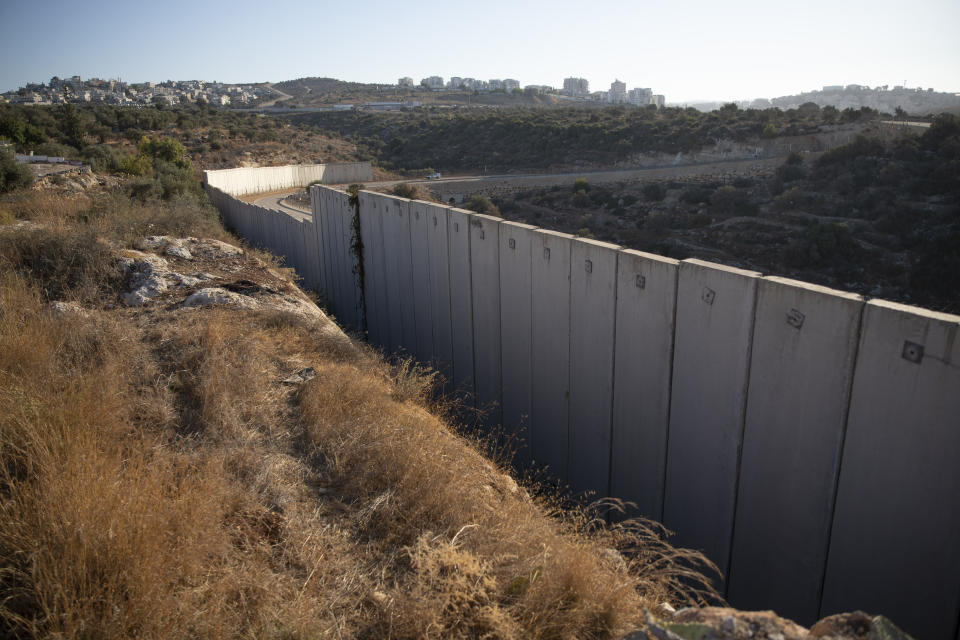 A section of Israel's separation barrier separates between the Israeli settlement of Modi'in Illit, right and the West Bank village of Nilin, west of Ramallah, Sunday, Nov. 7, 2021. Nearly two decades after Israel sparked controversy worldwide by building the barrier during a Palestinian uprising, it has become a seemingly permanent feature of the landscape — even as Israel encourages its citizens to settle on both sides. (AP Photo/Nasser Nasser)