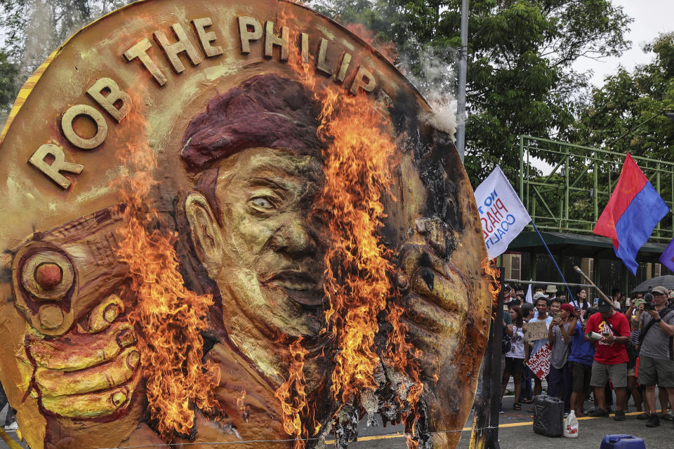 Protesters burn a two-faced gold coin effigy of President Ferdinand Marcos during a rally in Quezon City, Philippines, Monday, July 24, 2023, ahead of the second State of the Nation Address of Philippine President Ferdinand Marcos Jr. (AP Photo/Gerard Carreon)