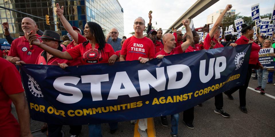 People in red union t-shirts carry a Stand Up sign as they march throughout downtown Detroit.