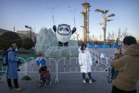 A woman poses for a photo with a statue of the Winter Olympics mascot Bing Dwen Dwen in Beijing, Jan. 12, 2022. (AP Photo/Mark Schiefelbein)
