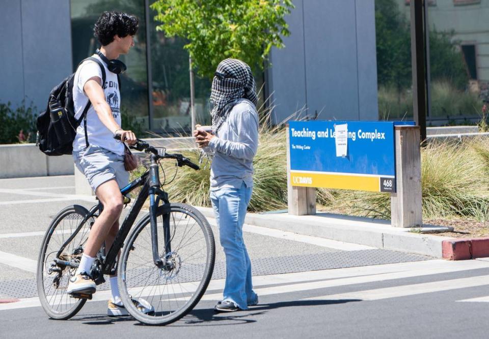 UC Davis graduating senior Taven Cunningham, left, speaks with pro-Palestinian protester and media liaison Raeda Zarzour on Monday, June 10, 2024, along Hutchison Drive at UC Davis. “I fundamentally disagree with how they’re going about it,” said Cunningham, who noted how this demonstration could hinder students’ ability to come to campus for their final exams. “I think there are more effective means.”