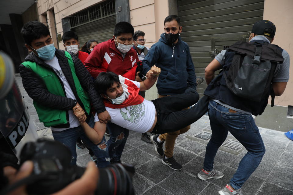 Police in civilian clothes detain a supporter of former President Martin Vizcarra as he and other protesters are blocked from reaching Congress to protest against the swearing-in of Manuel Merino, head of Peru's legislature, as the new president in Lima, Peru, Tuesday, Nov. 10, 2020. Congress voted to oust Vizcarra over his handling of the new coronavirus pandemic and unproven allegations of corruption years ago. (AP Photo/Rodrigo Abd)