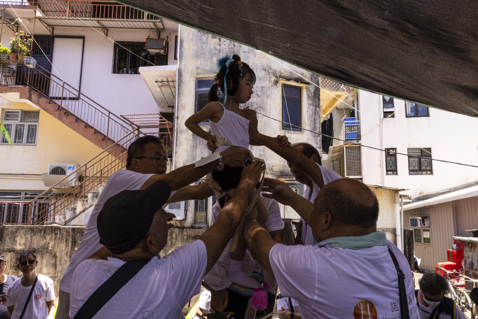 Workers prepare to hoist up a child for the Piu Sik Parade at Bun Festival in Cheung Chau Islandin the Piu Sik Parade at the Bun Festival in Cheung Chau Island in Hong Kong, Friday, May 26, 2023. (AP Photo/Louise Delmotte)