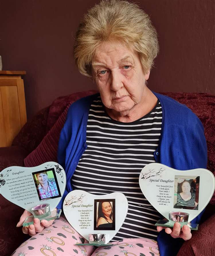 Denise Aitcheson holding pictures of her three daughters, Lisa, Laura, and Louise. (SWNS)