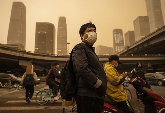 Commuters wear protective masks during a seasonal sandstorm in downtown Beijing